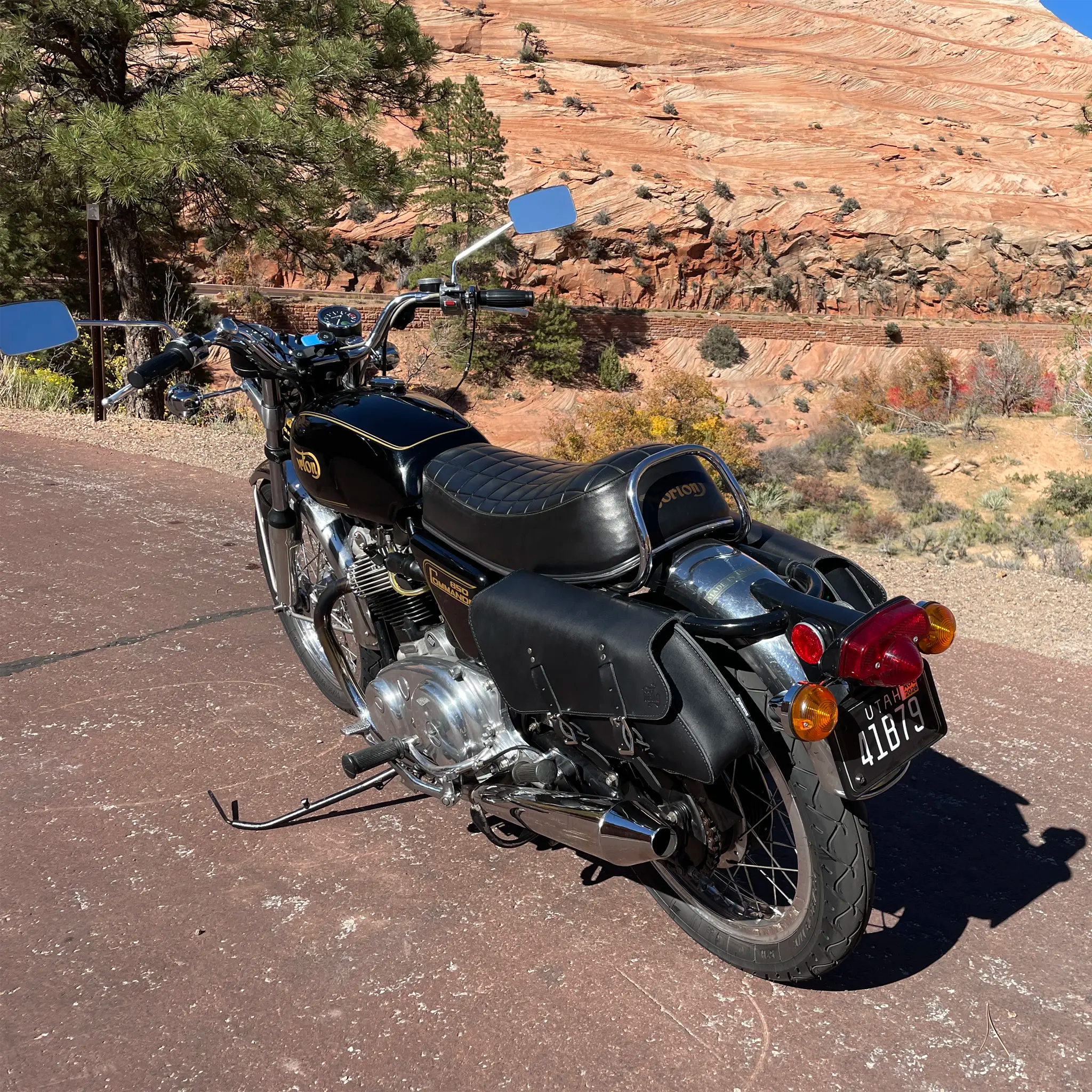 Black motorcycle parked on a road with a scenic background of mountains and trees.